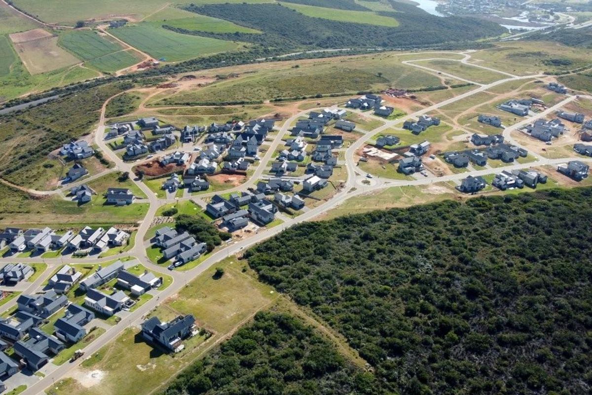 Aerial view of a residential estate development featuring multiple homes, paved roads, and surrounding natural landscape.