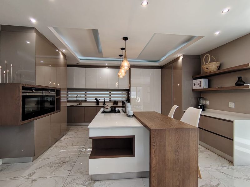Modern, high-end kitchen featuring sleek integrated cabinetry, a central island with breakfast bar, stone countertops, and premium built-in appliances.