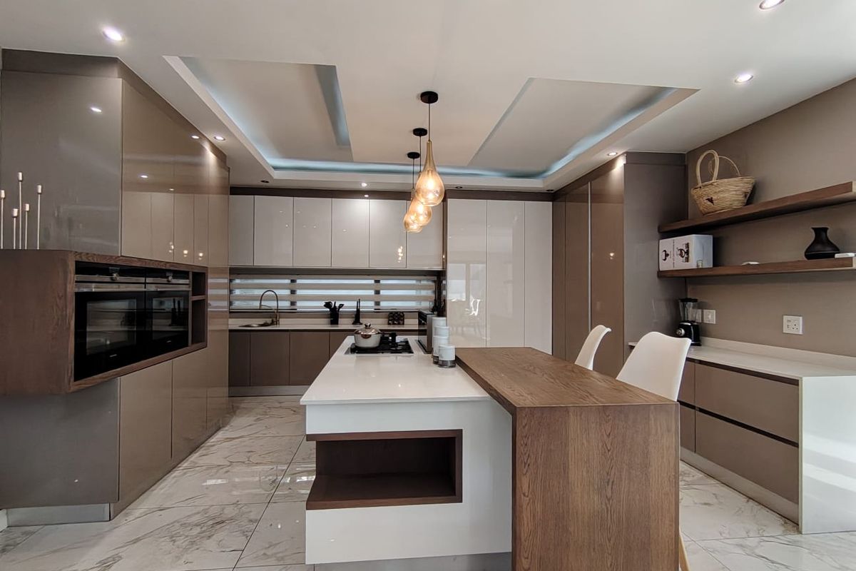 Modern, high-end kitchen featuring sleek integrated cabinetry, a central island with breakfast bar, stone countertops, and premium built-in appliances.