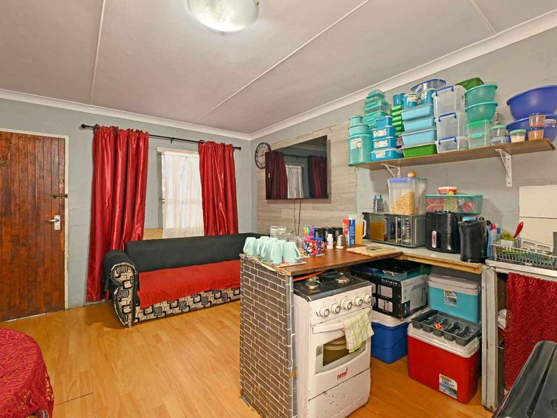 Open plan living and kitchen area featuring laminate flooring, a freestanding stove, and basic cabinetry, offering potential for modernization and improved layout.