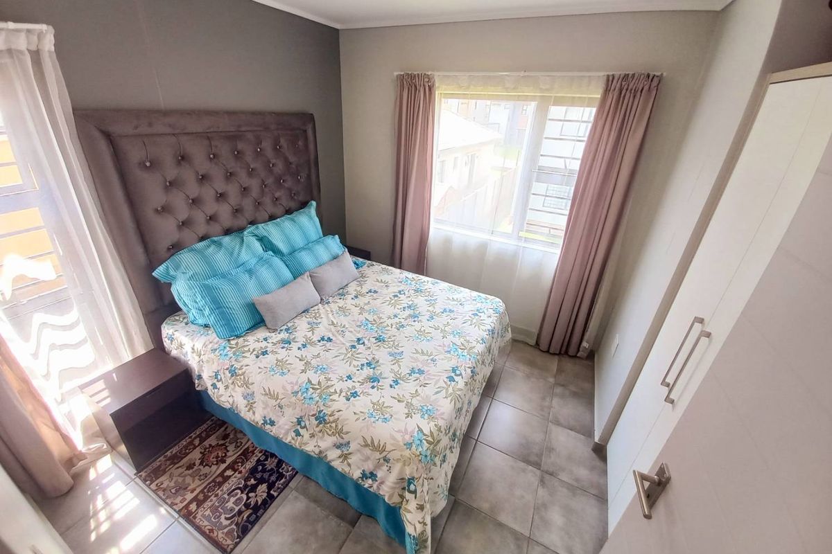A well-maintained bedroom featuring tiled flooring, a built-in wardrobe, and a window with curtain tracks, offering a clean and functional living space.