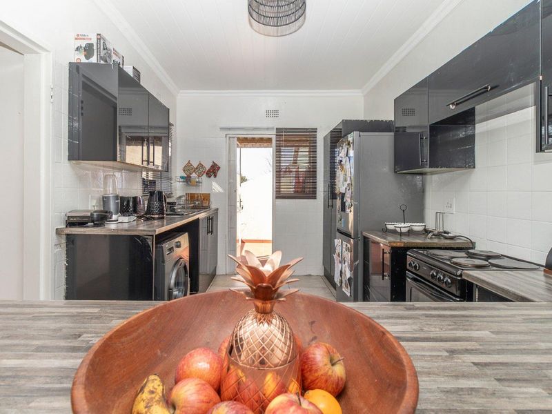 Functional kitchen featuring black high-gloss cabinetry, laminate countertops, tiled backsplash, and direct access to the exterior.