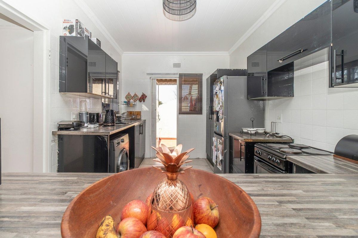 Functional kitchen featuring black high-gloss cabinetry, laminate countertops, tiled backsplash, and direct access to the exterior.