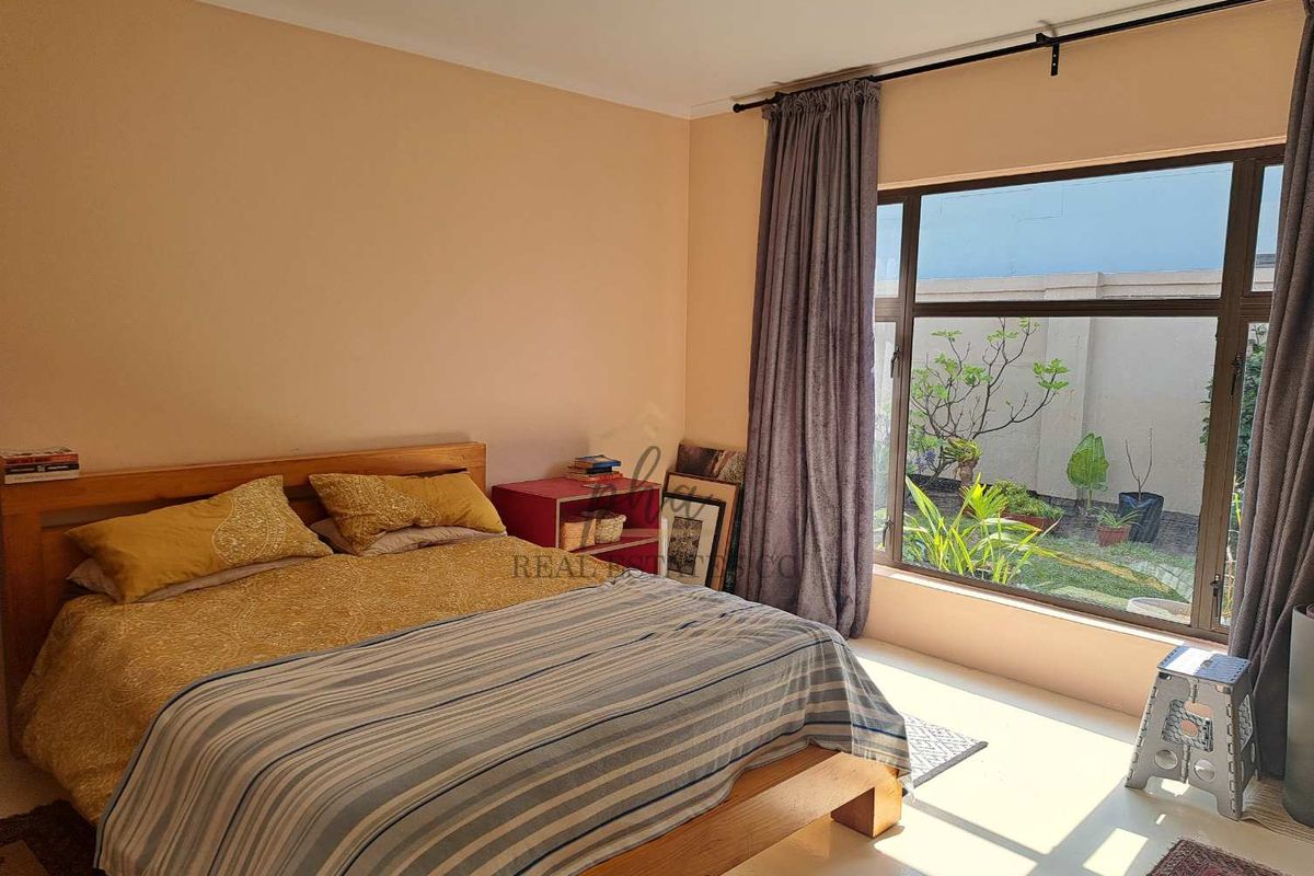 A bedroom featuring a large window with views of the garden, providing natural light and a connection to the outdoor space.