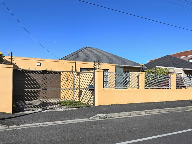 Front elevation of a residential property featuring a secure perimeter wall with electric fencing, a metal driveway gate, and a single garage.
