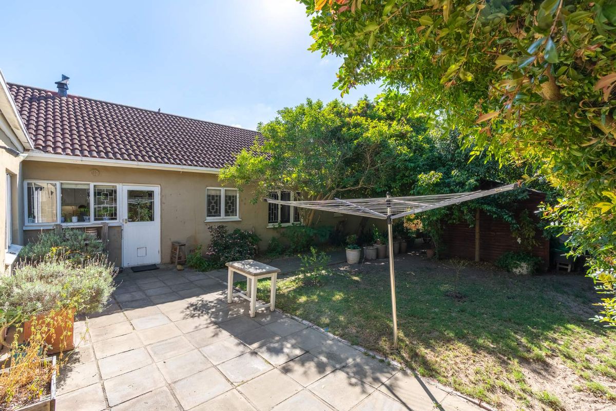 Rear view of the property featuring a paved patio area, established garden, and direct access to the home via a rear door.