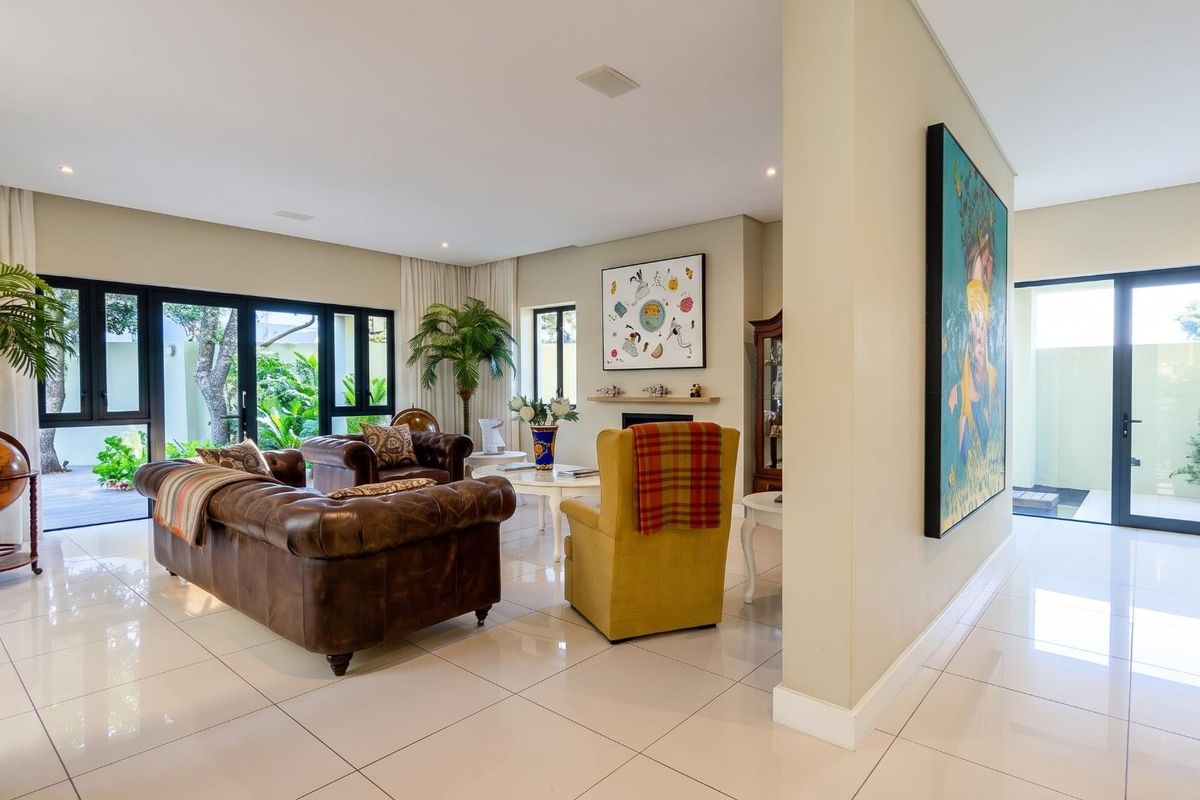 Spacious living room featuring polished porcelain floor tiles, recessed lighting, and large aluminium sliding doors providing seamless access to the outdoor patio area.
