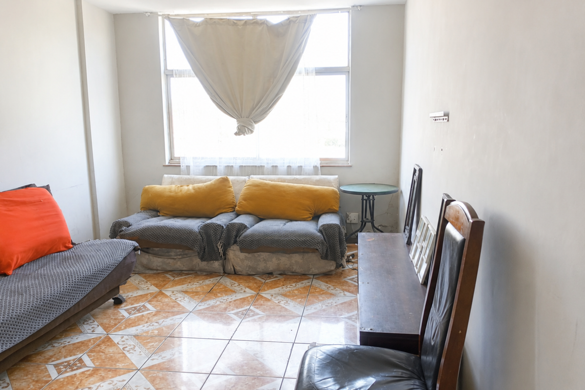A living room featuring large windows and patterned tile flooring, offering a blank canvas for potential renovation and interior design updates.