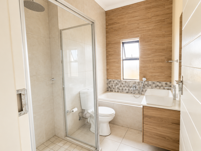 Modern bathroom featuring a glass-enclosed shower, built-in bathtub, vessel sink vanity, and contemporary wood-look and mosaic tile finishes.