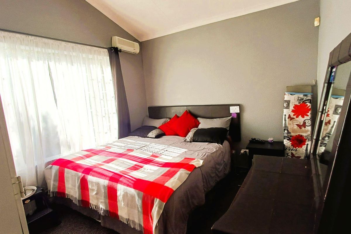 A bedroom featuring a vaulted ceiling and a wall-mounted split-system air conditioning unit.