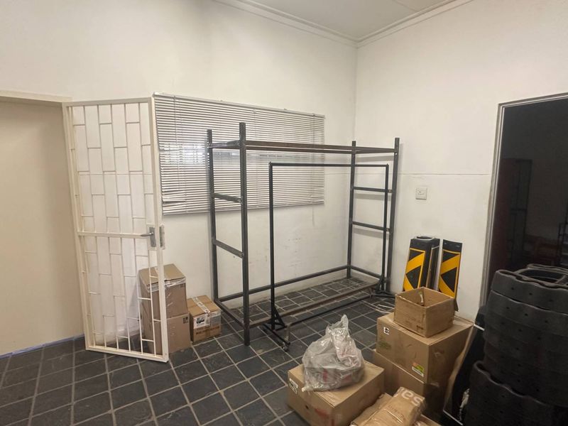 A functional utility space featuring tiled flooring, a security gate, and venetian blinds, currently used for storage.