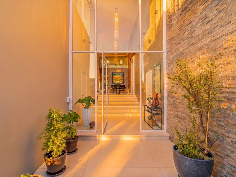 A striking modern entrance featuring a floor-to-ceiling glass facade, elegant stone cladding, and a welcoming staircase leading into the home.