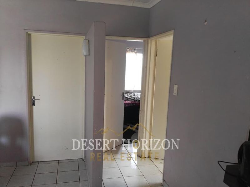 A functional hallway area featuring tiled flooring and multiple internal doors leading to adjacent rooms.