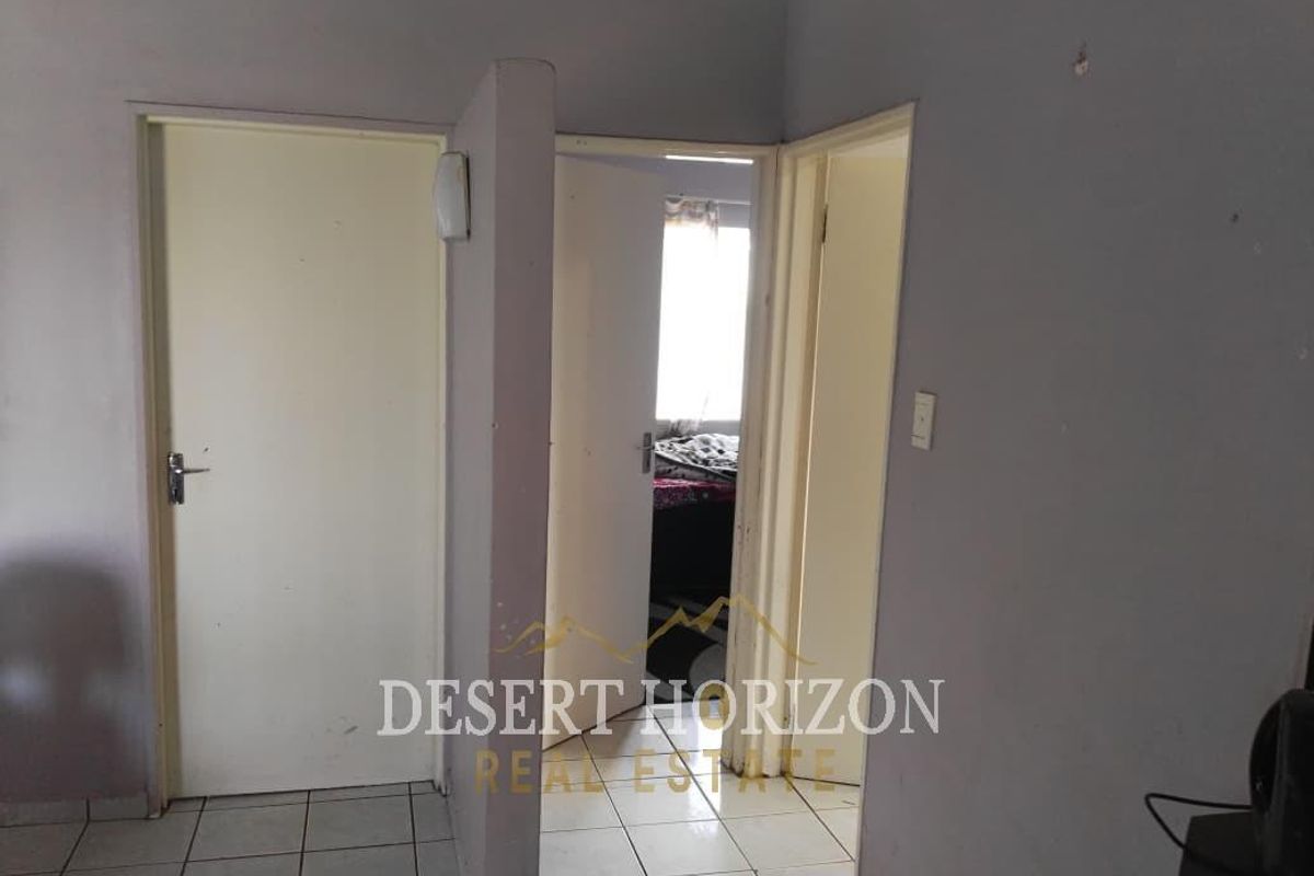 A functional hallway area featuring tiled flooring and multiple internal doors leading to adjacent rooms.
