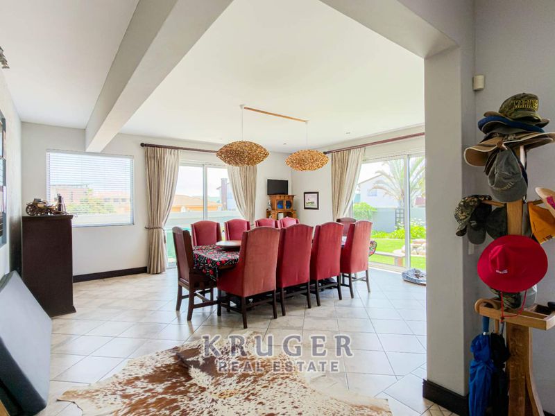 Spacious open-plan dining area featuring tiled flooring, large sliding glass doors providing natural light, and direct access to the outdoor garden space.