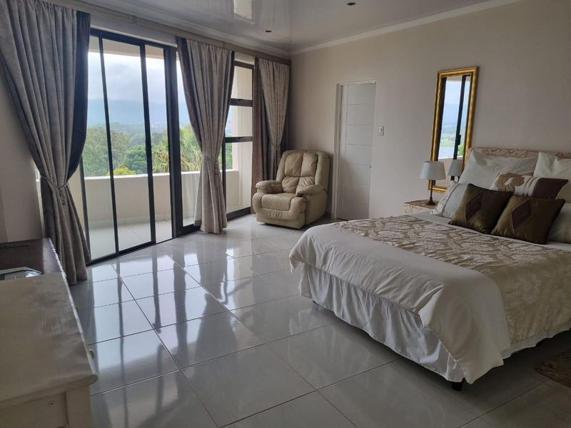 Spacious bedroom featuring large sliding glass doors leading to a private balcony, polished tile flooring, and neutral wall finishes.