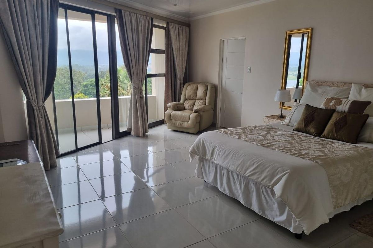 Spacious bedroom featuring large sliding glass doors leading to a private balcony, polished tile flooring, and neutral wall finishes.