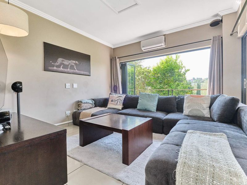 A comfortable living room featuring tiled flooring, a wall-mounted air conditioning unit, and large bi-fold doors that open to an outdoor area.