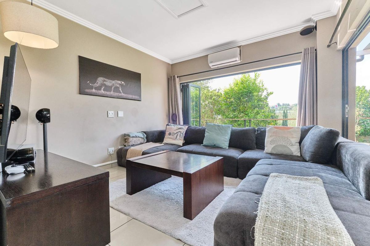 A comfortable living room featuring tiled flooring, a wall-mounted air conditioning unit, and large bi-fold doors that open to an outdoor area.