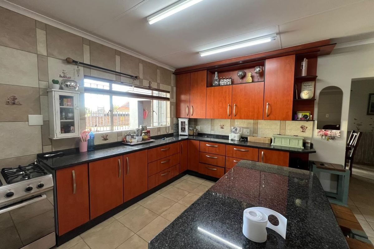 A functional kitchen featuring granite countertops, ample wooden cabinetry, a gas stove, and tiled flooring with a neutral splashback.