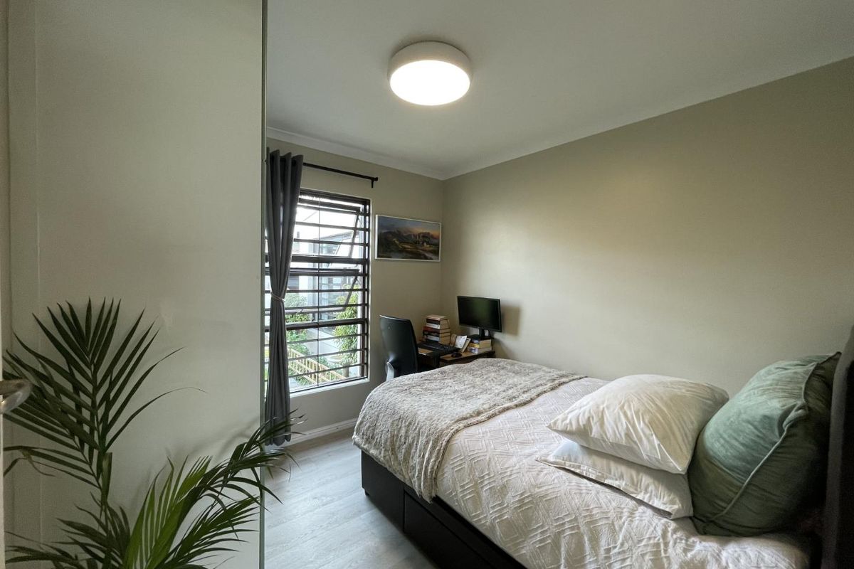 A well-maintained bedroom featuring light-toned laminate flooring, a built-in wardrobe, and a flush mount ceiling light fixture.