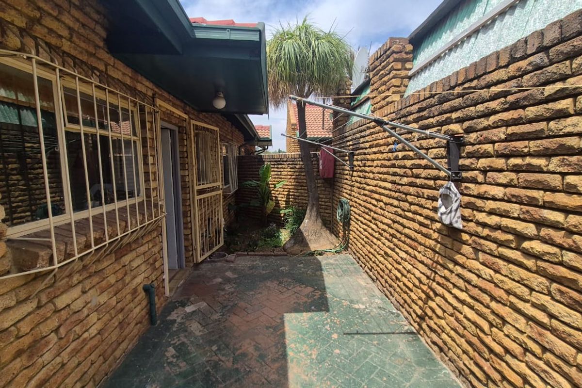 A private rear courtyard featuring face brick walls, paved flooring, and a wall-mounted washing line, providing a functional outdoor utility space.