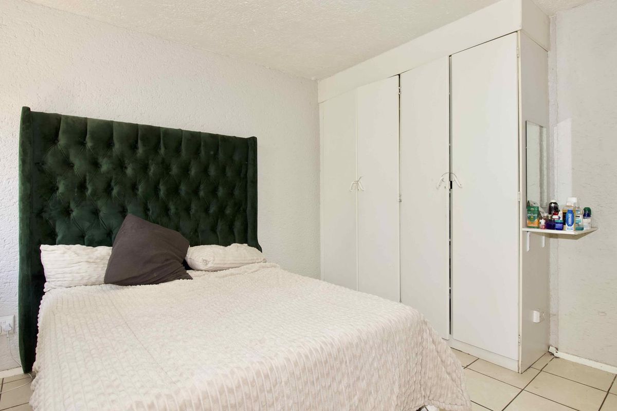 A bedroom featuring built-in white cabinetry and tiled flooring, providing functional storage space.