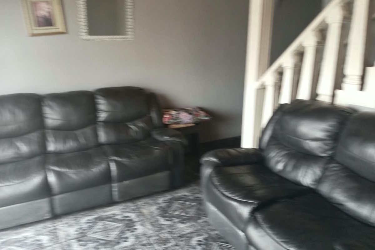 A living room area featuring a staircase with a white balustrade, finished with patterned flooring.