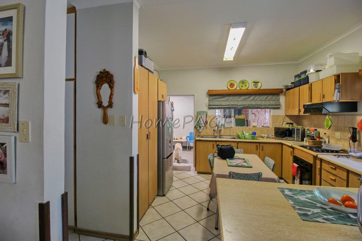 Functional kitchen featuring wooden cabinetry, tiled flooring, built-in oven, and hob, with an adjacent scullery area.