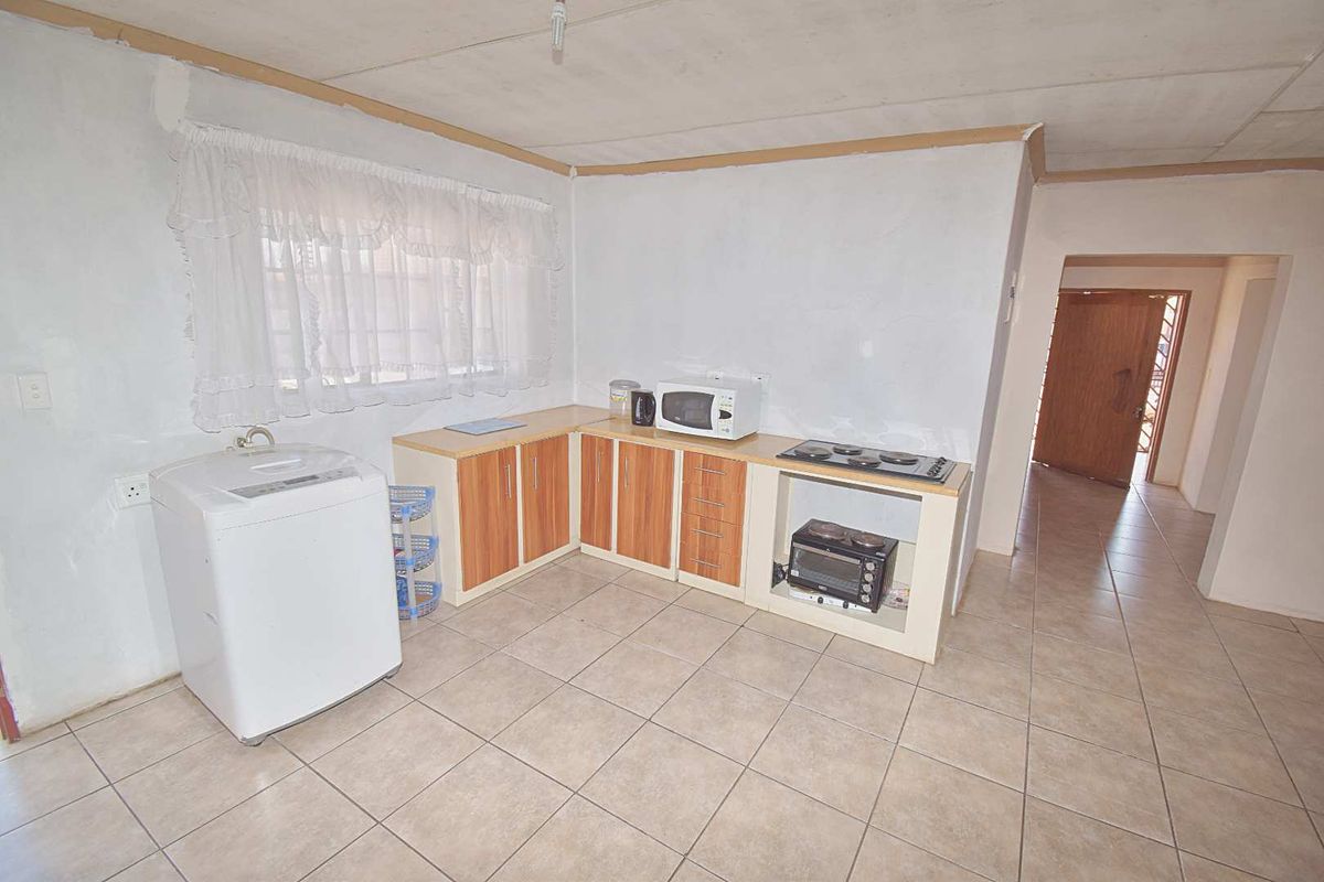 A functional kitchen area featuring tiled flooring, built-in cabinetry, and integrated cooking appliances, requiring cosmetic updates to improve the overall finish.