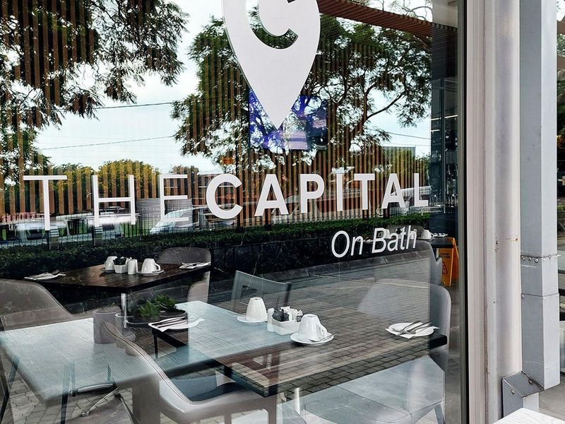 Exterior view of a commercial storefront with large glass windows and branding for The Capital on Bath.