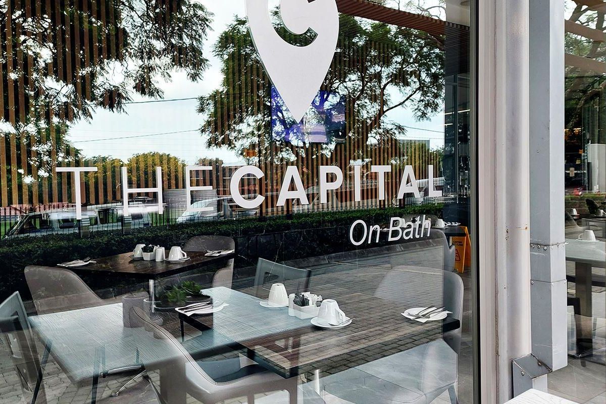 Exterior view of a commercial storefront with large glass windows and branding for The Capital on Bath.