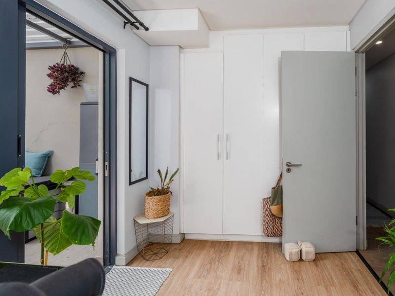 A bright hallway featuring modern laminate flooring, floor-to-ceiling built-in cupboards, and a sliding door providing access to an outdoor patio area.