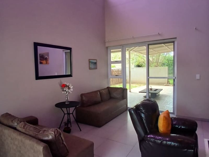 Spacious living room featuring high vaulted ceilings, large skylight, and tiled flooring, with direct access to an outdoor patio area through sliding glass doors.