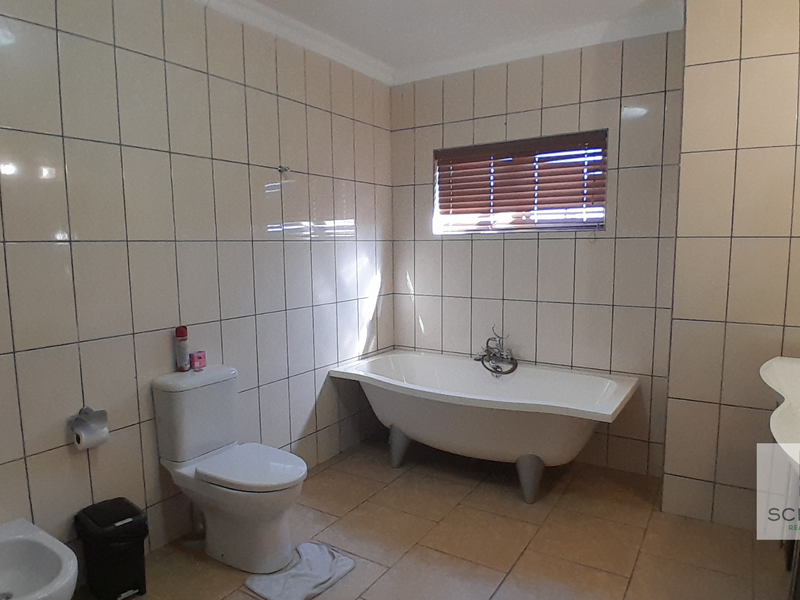 A spacious bathroom featuring a freestanding bathtub, bidet, toilet, and vanity basin with neutral wall and floor tiling.