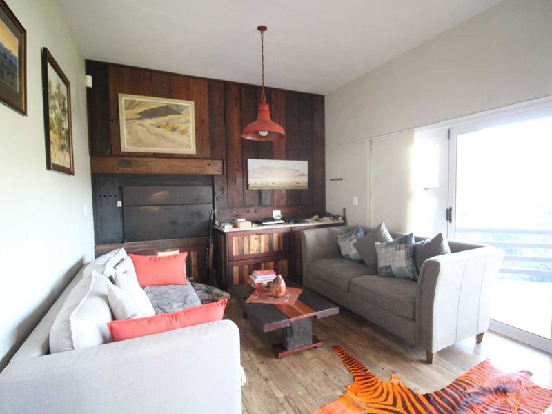 A cozy living room featuring a prominent wood-paneled accent wall with a built-in fireplace and direct access to an outdoor area via sliding glass doors.