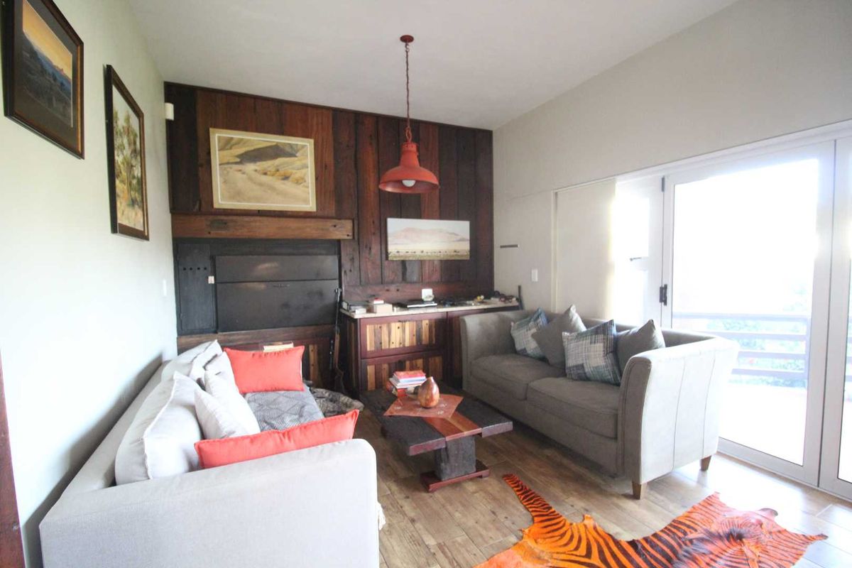 A cozy living room featuring a prominent wood-paneled accent wall with a built-in fireplace and direct access to an outdoor area via sliding glass doors.