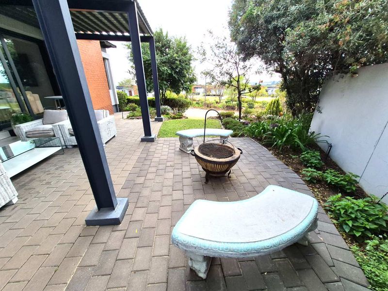 A paved outdoor patio area featuring a pergola structure, providing a pleasant space for outdoor relaxation and garden views.