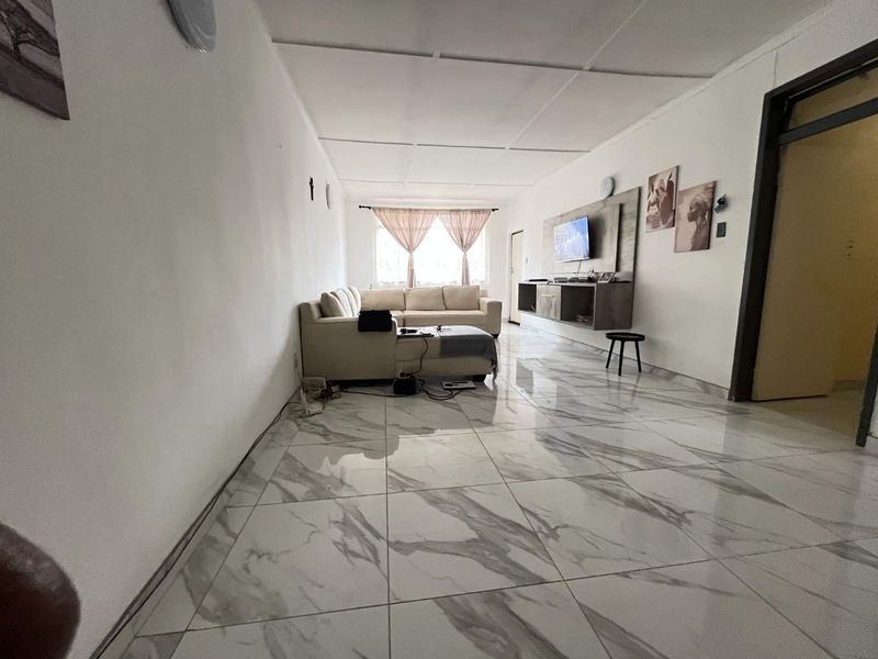 Spacious living room featuring large-format marble-look floor tiles and a built-in media console unit.