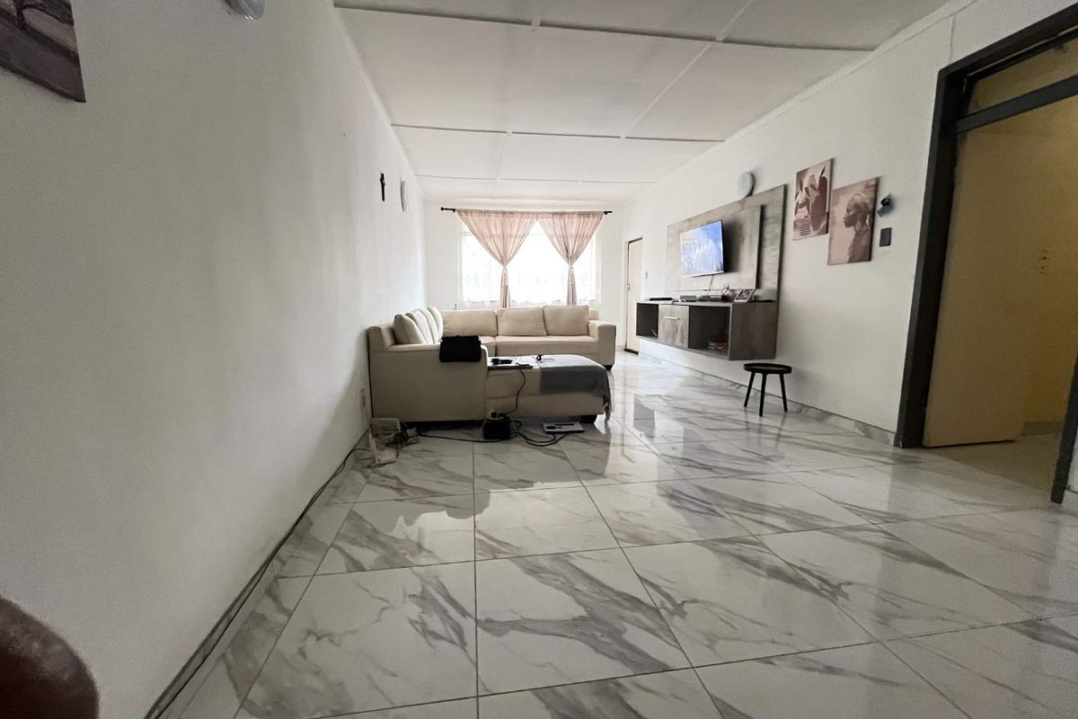 Spacious living room featuring large-format marble-look floor tiles and a built-in media console unit.