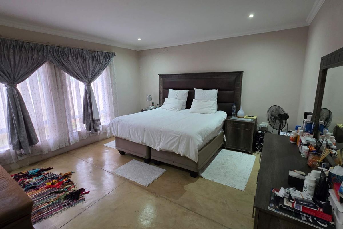 Spacious bedroom featuring polished concrete flooring, recessed downlighting, and large windows with curtains, offering a neutral canvas for personalization.