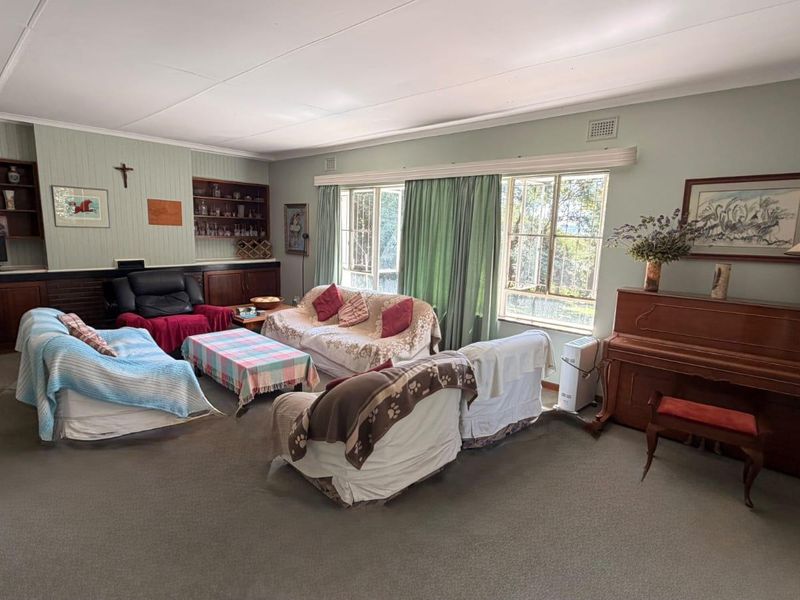 Spacious living room featuring built-in wooden cabinetry, shelving, and large windows that provide ample natural light.