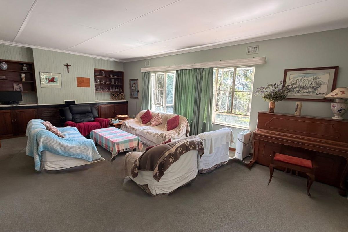 Spacious living room featuring built-in wooden cabinetry, shelving, and large windows that provide ample natural light.