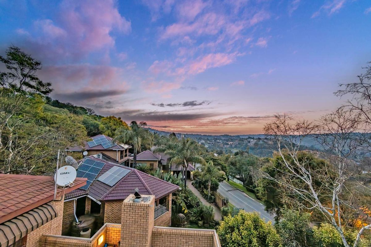 Elevated aerial view showcasing the property's roof structure, solar panels, and surrounding landscape at sunset.