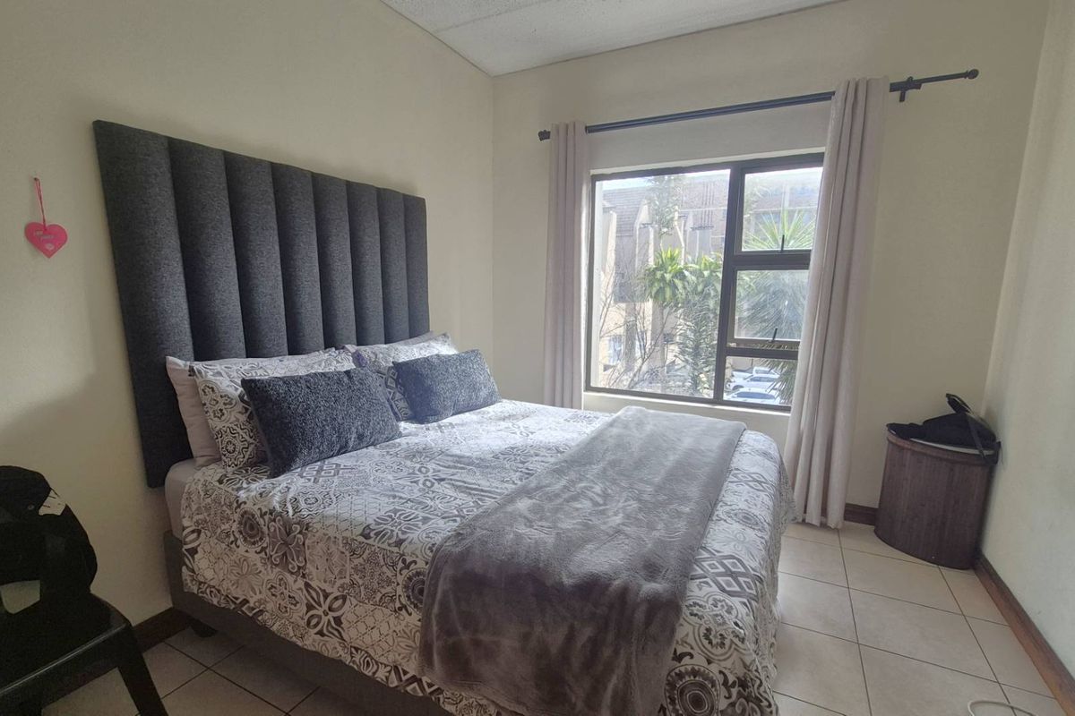 A well-lit bedroom featuring tiled flooring and a large window that allows for natural light.