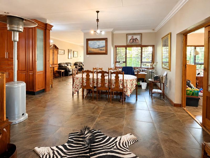 Spacious open-plan living and dining area featuring large format floor tiles, extensive built-in wooden cabinetry, and classic sliding wooden doors.