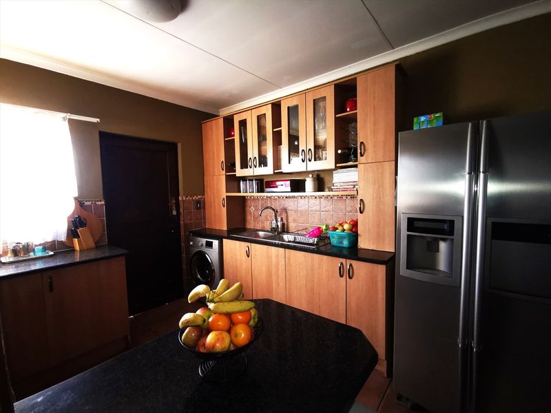 A functional kitchen featuring wooden cabinetry, granite countertops, tiled backsplash, and integrated appliances, offering a practical layout for daily meal preparation.