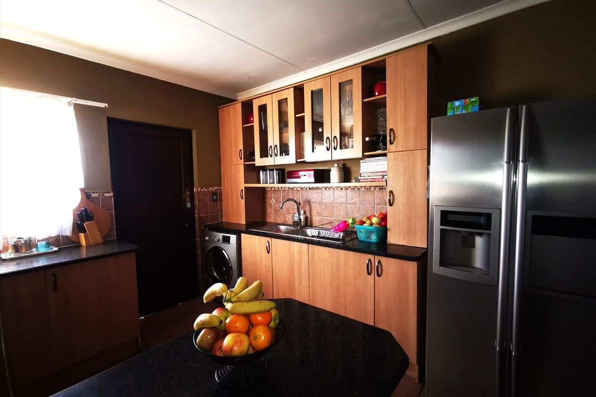 A functional kitchen featuring wooden cabinetry, granite countertops, tiled backsplash, and integrated appliances, offering a practical layout for daily meal preparation.