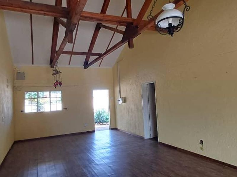 Spacious living area featuring high vaulted ceilings with exposed timber trusses and laminate flooring, offering a bright and open layout.