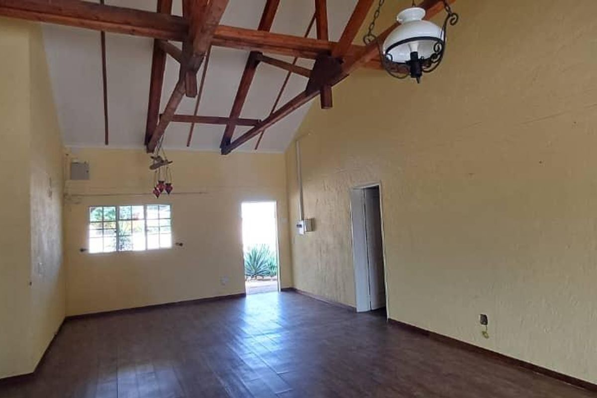 Spacious living area featuring high vaulted ceilings with exposed timber trusses and laminate flooring, offering a bright and open layout.